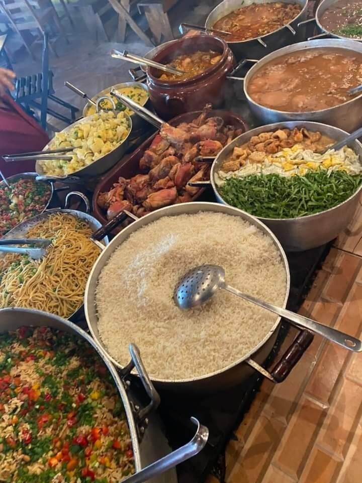 Cozinha caseira acolhedora com panelas e ingredientes frescos sendo preparados por pessoas reais